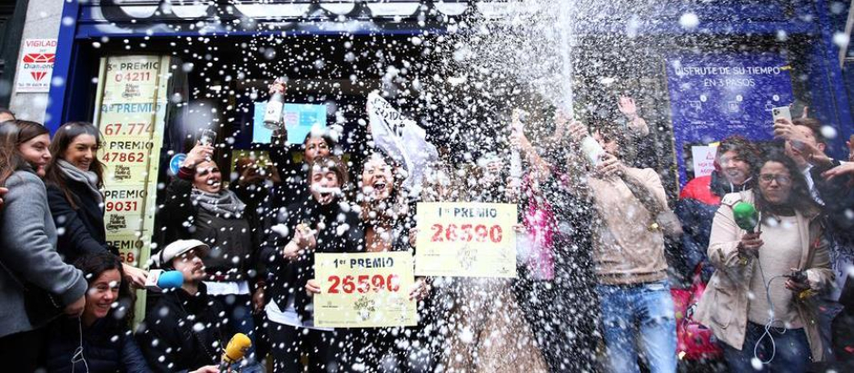 Un grupo de personas agraciadas con el Gordo de la Lotería lo celebra en la administración madrileña de Doña Manolita en 2019