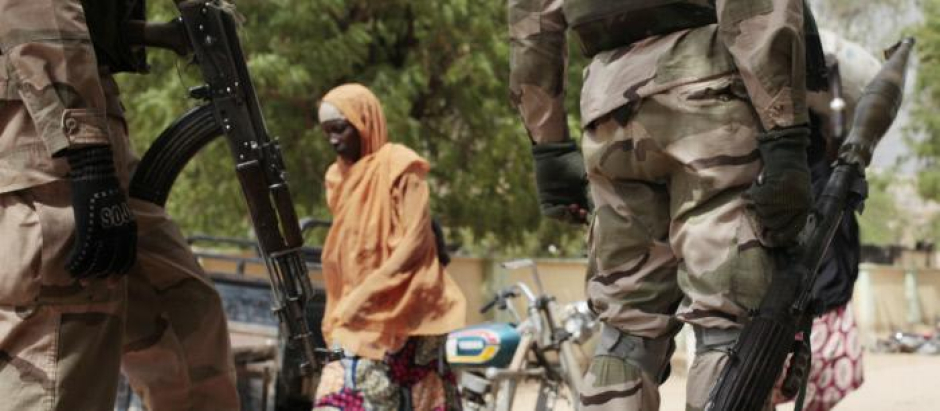 Una mujer pasea frente a unos militares en Gwoza, ciudad liberada por el ejército nigeriano en 2015.