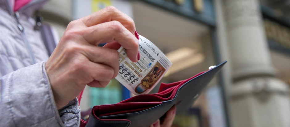 Una mujer guarda en la cartera el décimo de lotería de Navidad que ha comprado en una administración