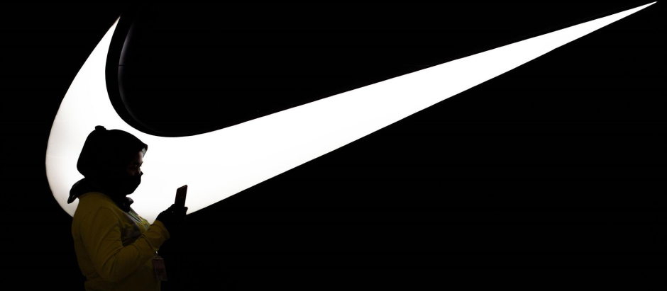Una mujer pasea delante del logotipo de Nike.