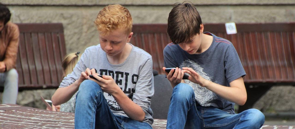 Dos jóvenes jugando un teléfono móvil.