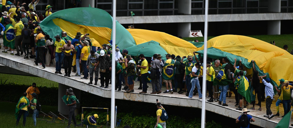 Manifestantes portan una gran bandera de Brasil en su asalto al Congreso
