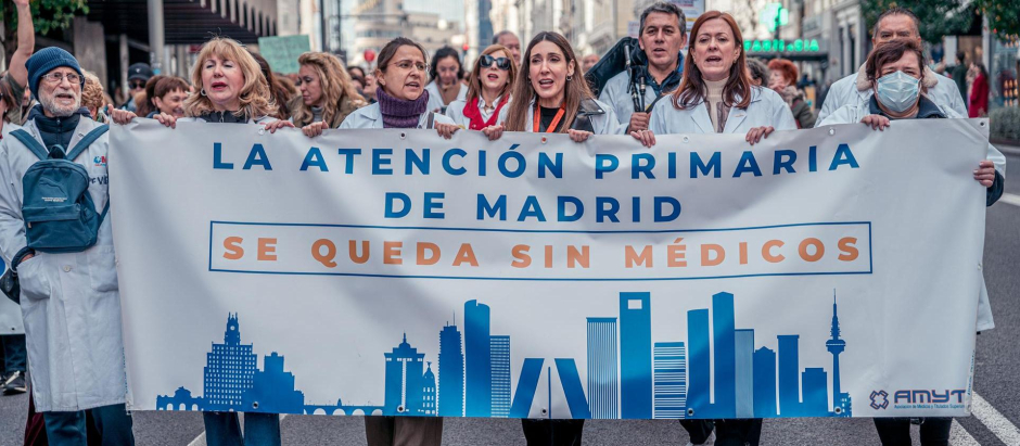 Varias personas caminan llevando una pancarta que reza 'La atención primaria de Madrid se queda sin médicos' durante una manifestación de médicos y pediatras