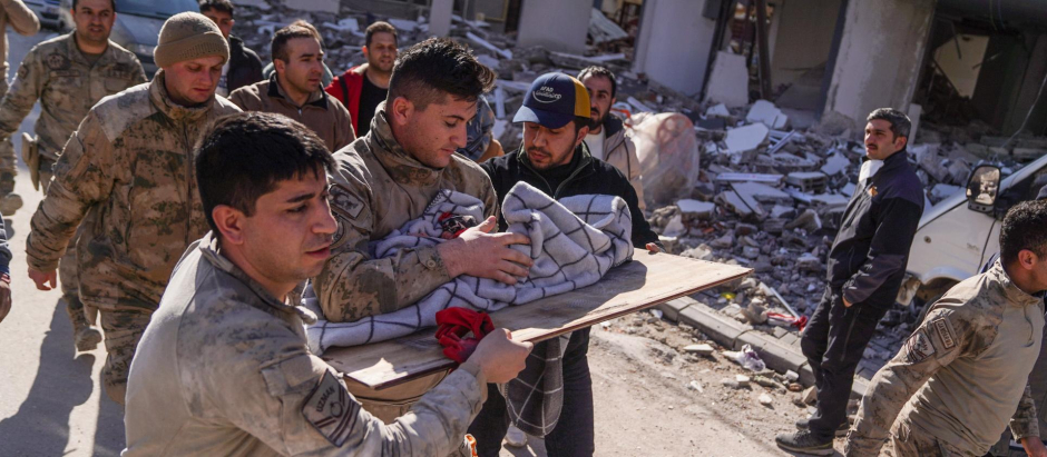 Un grupo de personas trasladan a un bebé que acaban de sacar de debajo de los escombros tras el terremoto en Hatay (Turquía)
