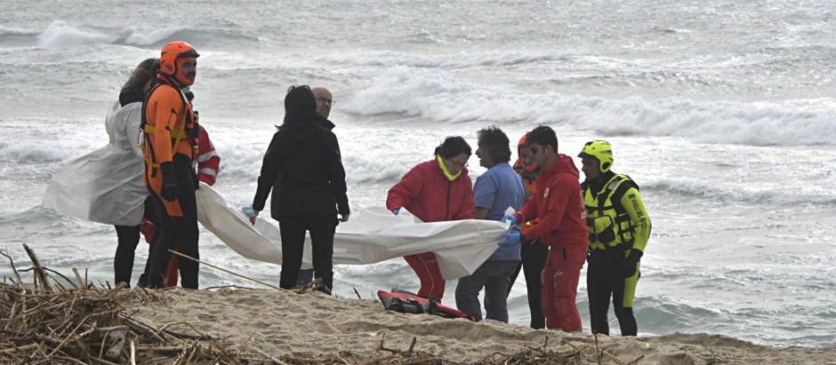 Los bomberos italianos y la Cruz Roja se reúnen en el lugar donde los cuerpos de los migrantes llegaron a la costa después de un naufragio