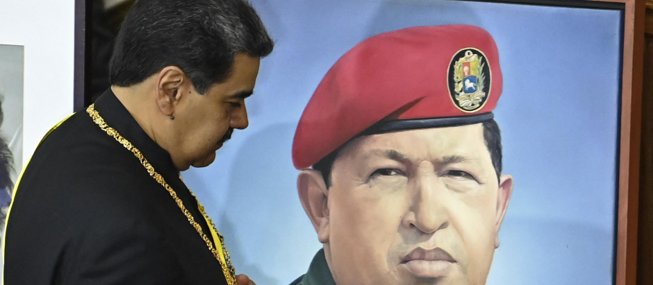 Nicolás Maduro, pasa junto a un retrato del difunto presidente Hugo Chávez mientras presenta su informe anual a la Asamblea Nacional en Caracas