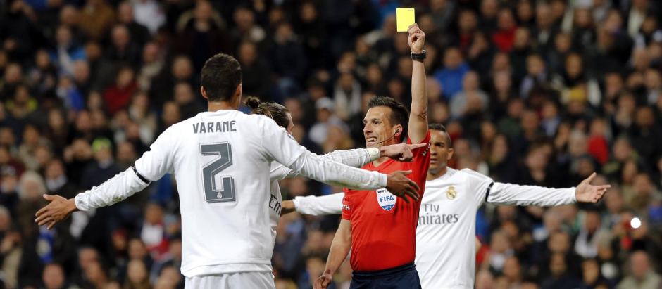 Estrada Fernández mostrando la cartulina amarilla a un jugador del Real Madrid
