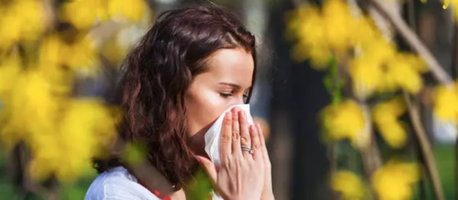 Una mujer sufre los efectos de la alergia en un parque