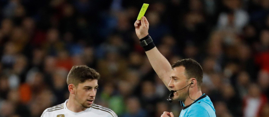 El colegiado Felix Zwayer muestra la cartulina amarilla al centrocampista uruguayo del Real Madrid Federico Valverde