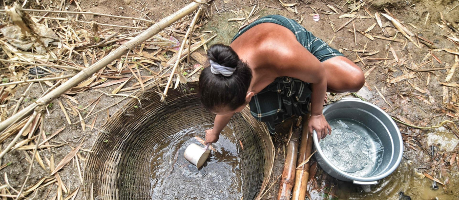 Una mujer recoge agua de un pozo en el río Cihoe