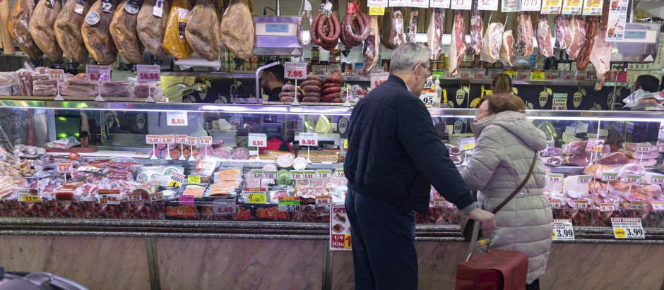 Una pareja compra en una charcutería en un mercado de Madrid.