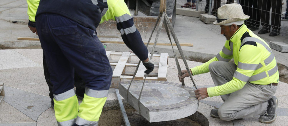 Operarios instalando la placa del Kilómetro Cero en la Puerta del Sol