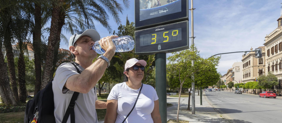 Un hombre bebe agua el pasado viernes en Murcia junto a un termómetro que marca 35 grados