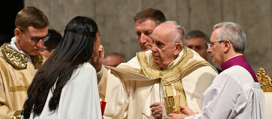 El Papa Francisco da la comunión a una mujer recién bautizada, durante la misa de la Vigilia Pascual