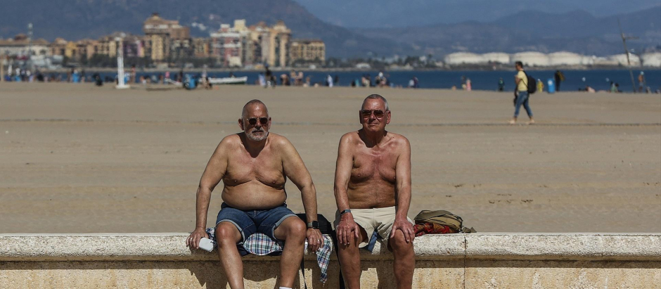 Dos hombres toman el sol en la playa de La Malvarrosa, en Valencia