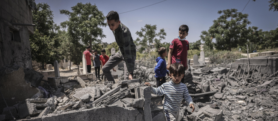 People inspect the damage in a graveyard hit by an Israeli air strike in Beit Lahia in the northern Gaza Strip, on May 13, 2023. Israeli air strikes battered Gaza again on May 13 in response to rocket fire from militants as deadly fighting resumed after a night of relative calm, despite efforts to secure a truce. (Photo by MOHAMMED ABED / AFP)