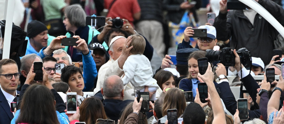 Pope Francis (CL) blesses a child as he arrives for the weekly general audience at St. Peter's square in The Vatican on May 17, 2023. (Photo by Andreas SOLARO / AFP)