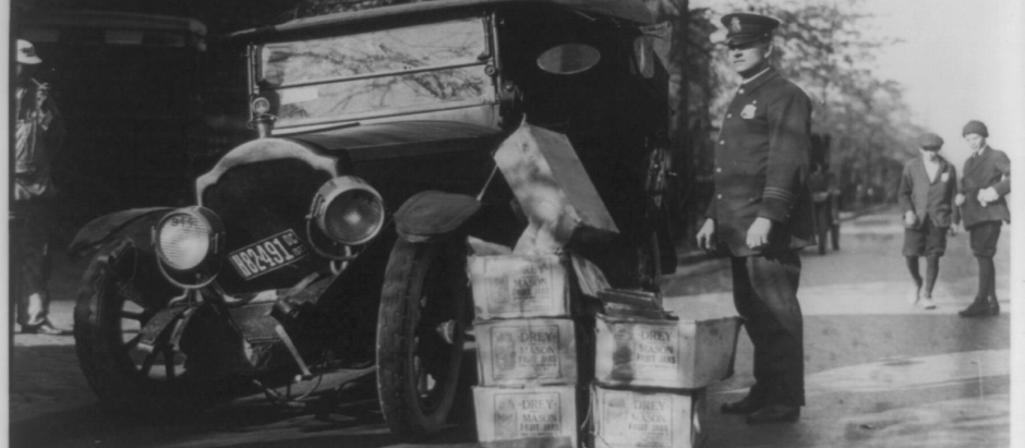 Un policía con un automóvil destrozado y alcohol ilegal confiscado, 1922