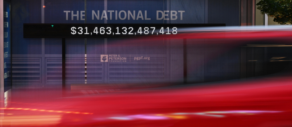 Un coche pasa frente a una parada de autobús que muestra la deuda nacional en Washington, DC
