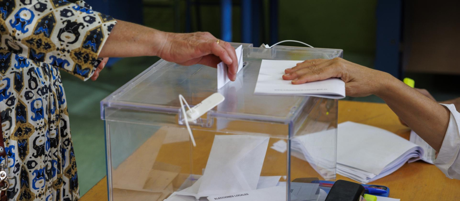 Una mujer introduce su voto en una urna en un colegio electoral del centro de Sevilla