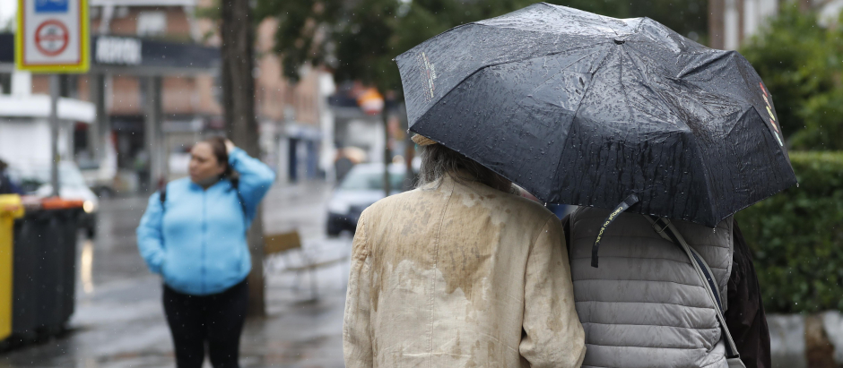 Una pareja intenta protegerse de la lluvia este martes en Madrid