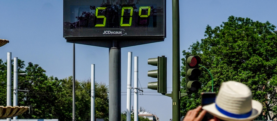 Transeúntes fotografían el termómetro situado en el Prado que marca 50 grados, a 26 de junio del 2023 en Sevilla
