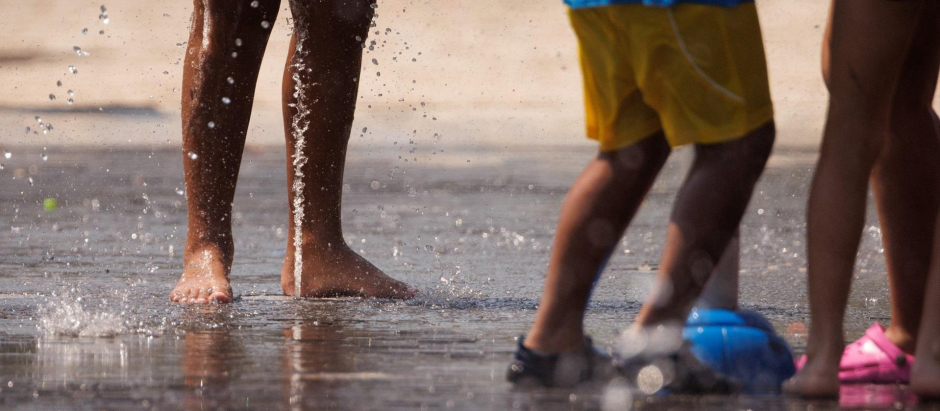 Varias personas juegan en el agua para refrescarse en Madrid Rio