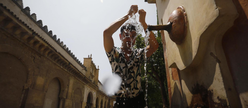 Un joven se refresca en una fuente de del Patio de los Naranjos de la Mezquita-Catedral de Córdoba