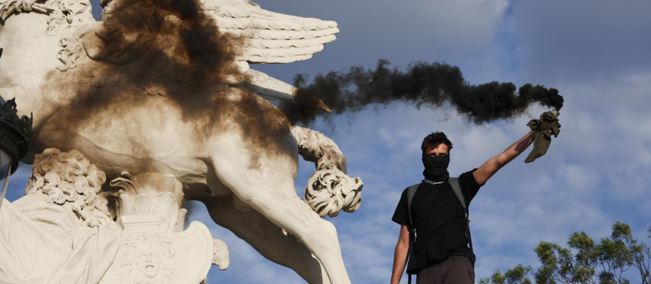 Un manifestante sostiene una bengala de humo durante una protesta en memoria de Nahel