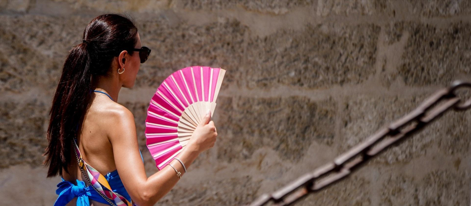 Una  turista, con un abanico en la mano por los alrededores de la Catedral de Sevilla