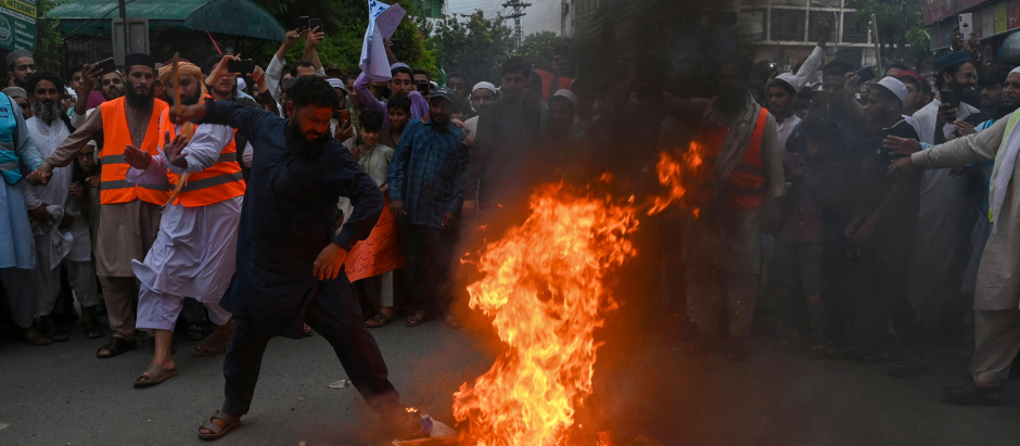 People burn Sweden's flag during a demonstration in Lahore on July 9, 2023, as they protest against the burning of the Koran outside a Stockholm mosque that outraged Muslims around the world. (Photo by Arif ALI / AFP)