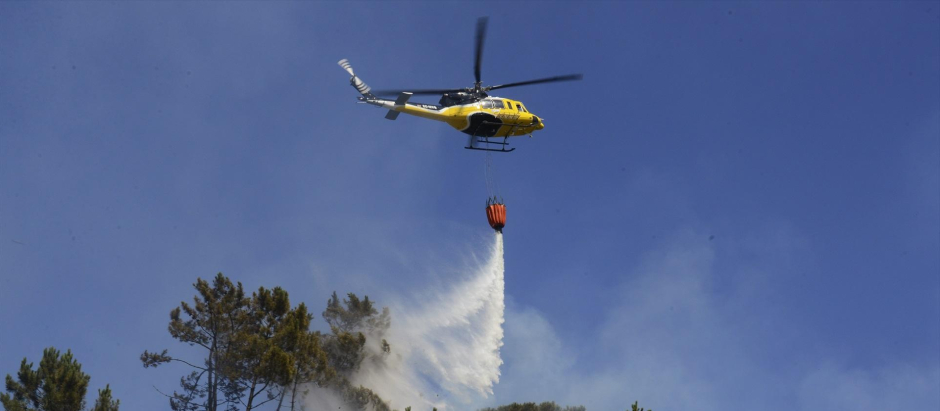 Un helicóptero arroja agua sobre un incendio forestal