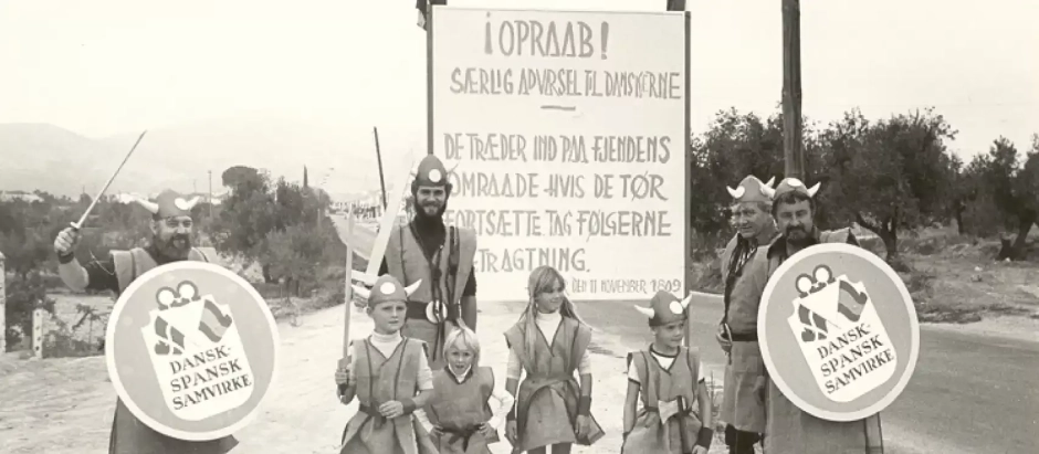 Ciudadanos daneses que fueron al pueblo de Huéscar (Granada) a la 'firma del tratado' de paz con su país, con el lema de 'amistad hispano-danesa', escrito en su idioma, en los escudos
