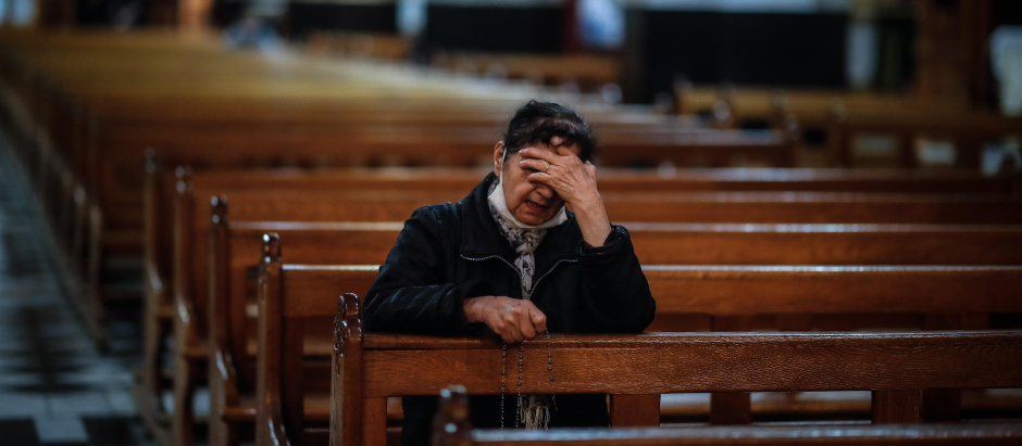 Una mujer reza sola en una iglesia durante la pandemia