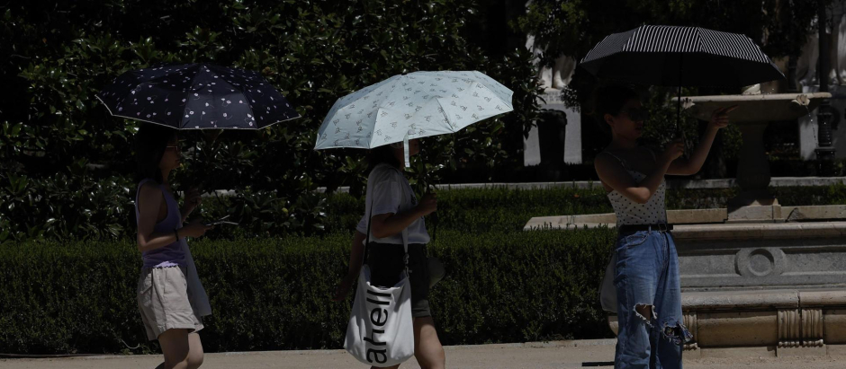 Varios viandantes se protegen del sol con paraguas este sábado en la Plaza de Oriente de Madrid