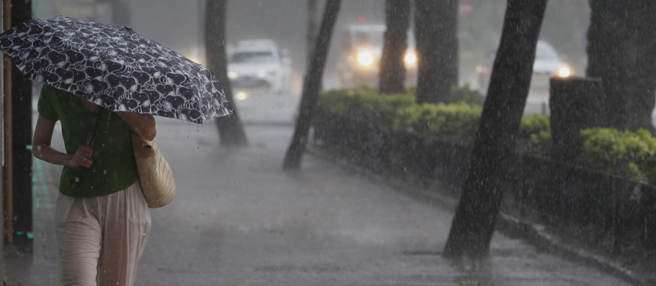 Una mujer camina por la acera bajo una intensa lluvia en Valencia