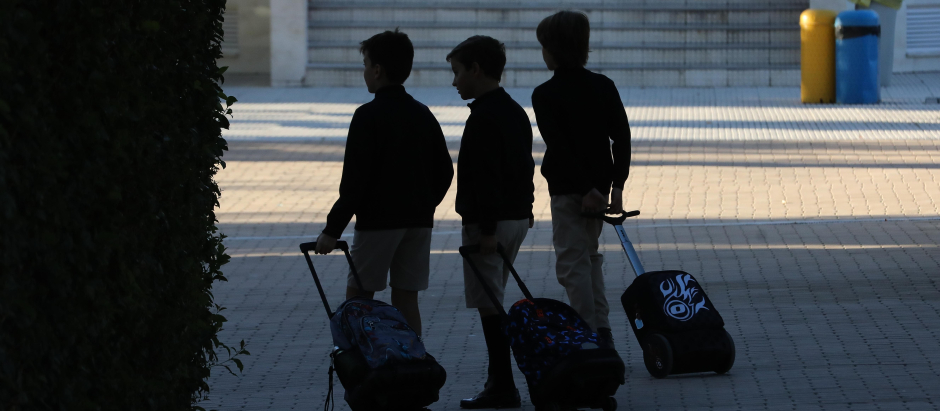 Tres niños en la entrada de su colegio