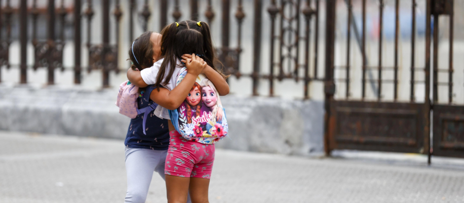 Dos niñas se abrazan en la puerta del colego