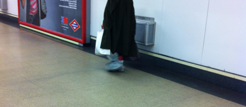 Pobre calzado con bolsas en los pies en el Metro