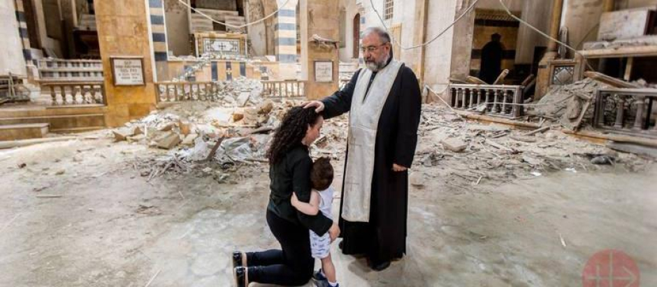 Un sacerdote sirio consuela a una familia cristiana