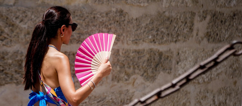 Una turista con un abanico en la mano por los alrededores de la Catedral de Sevilla