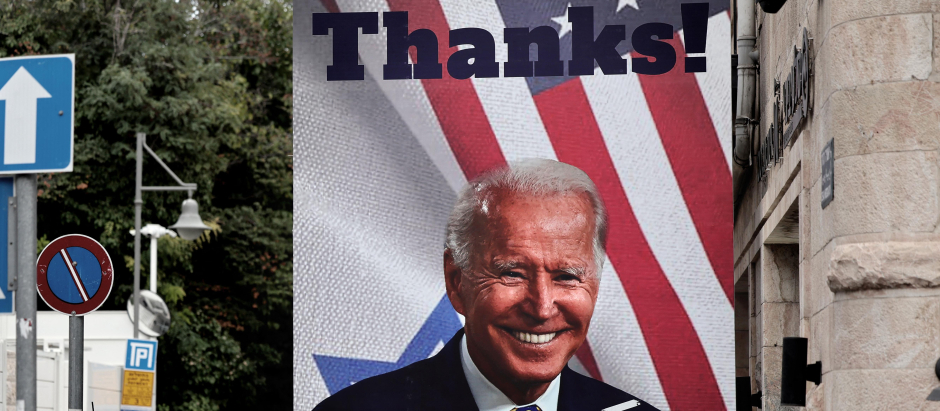 Un hombre pasa junto a un cartel gigante del presidente estadounidense Joe Biden en una calle de Jerusalén,