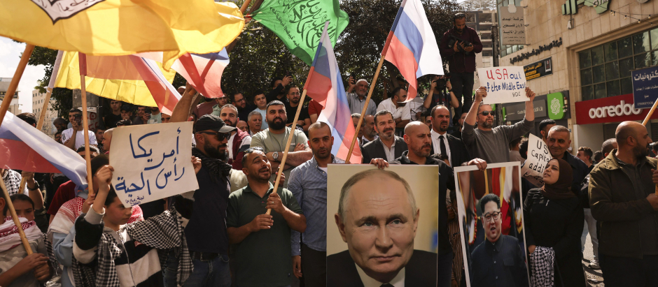 La gente ondea banderas rusas, palestinas, Fatah y Hamas, y porta retratos del presidente ruso Vladimir Putin y del líder norcoreano Kim Jong Un, en Cisjordania