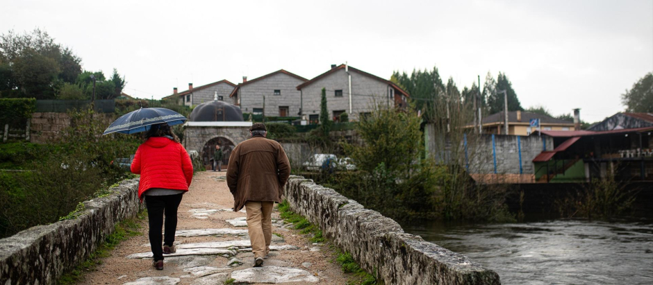 Varias personas cruzan un puente observando la crecida del río Tea en Ponteareas, Pontevedra