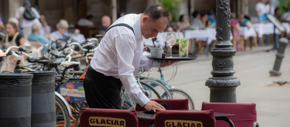Un camarero limpia una mesa en la plaza Real de Barcelona