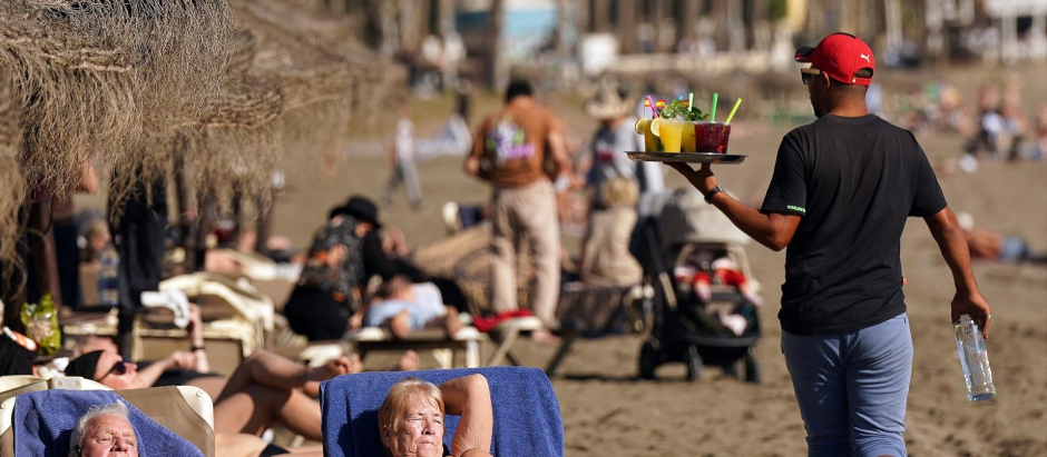 Varias personas disfrutan tomando el sol en la playa de la Malagueta a 12 de diciembre