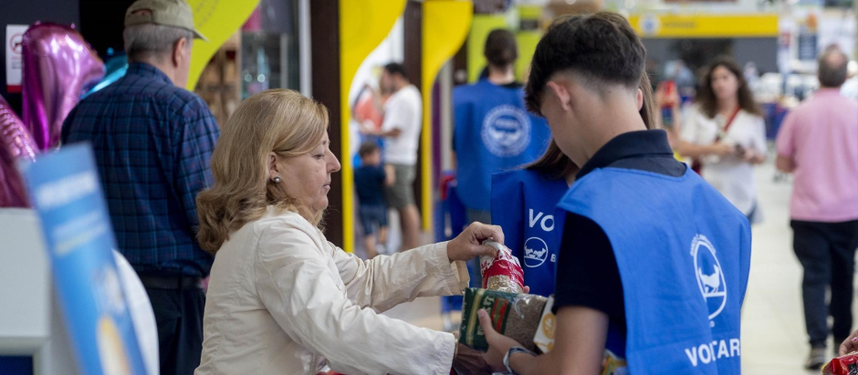 Una mujer dona a un voluntario alimentos durante la 'Operación Kilo'