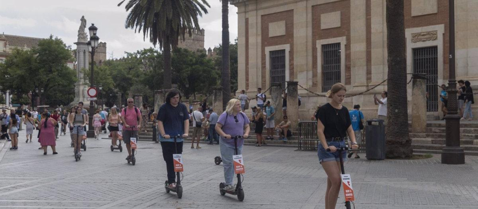 Turistas en patinete eléctrico paseando por el entorno de la Catedral de Sevilla