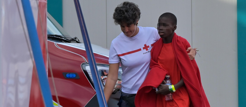 Una voluntaria de cruz roja asiste a un inmigrante en El Hierro