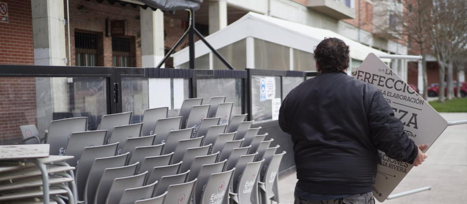 Un camarero coloca sillas de una terraza de una céntrica calle de Pamplona.